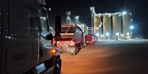 Line of trucks waiting at an illuminated sand plant at night.