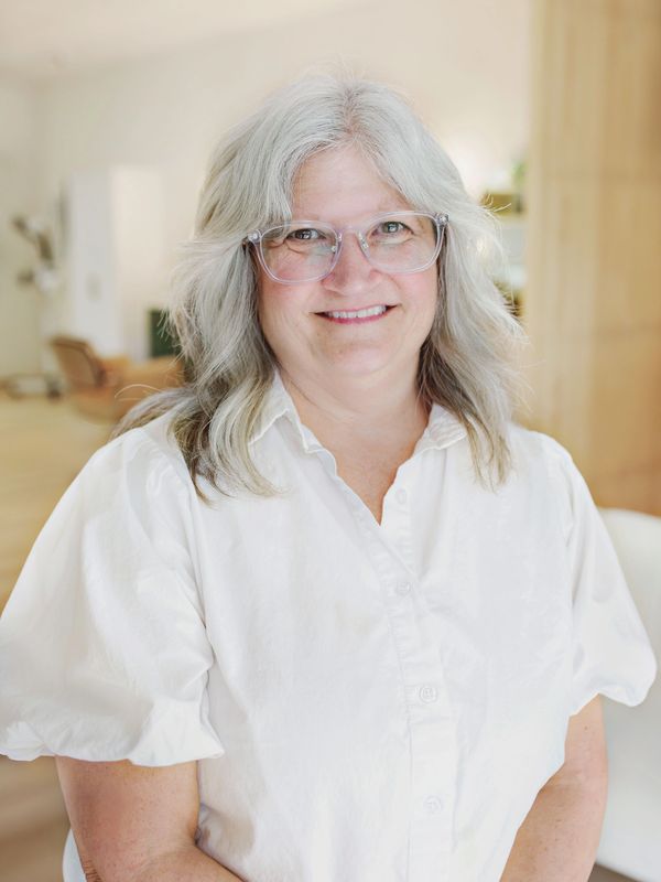Smiling woman with gray hair and glasses.