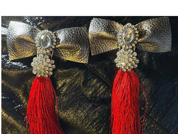 Elegant silver bows with crystal accents and vibrant red tassels on black textured background.