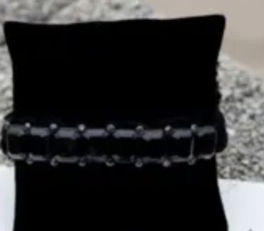Black beaded bracelet on a black cushion display.