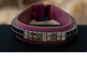 A close-up of a purple wristband with metallic square embellishments.