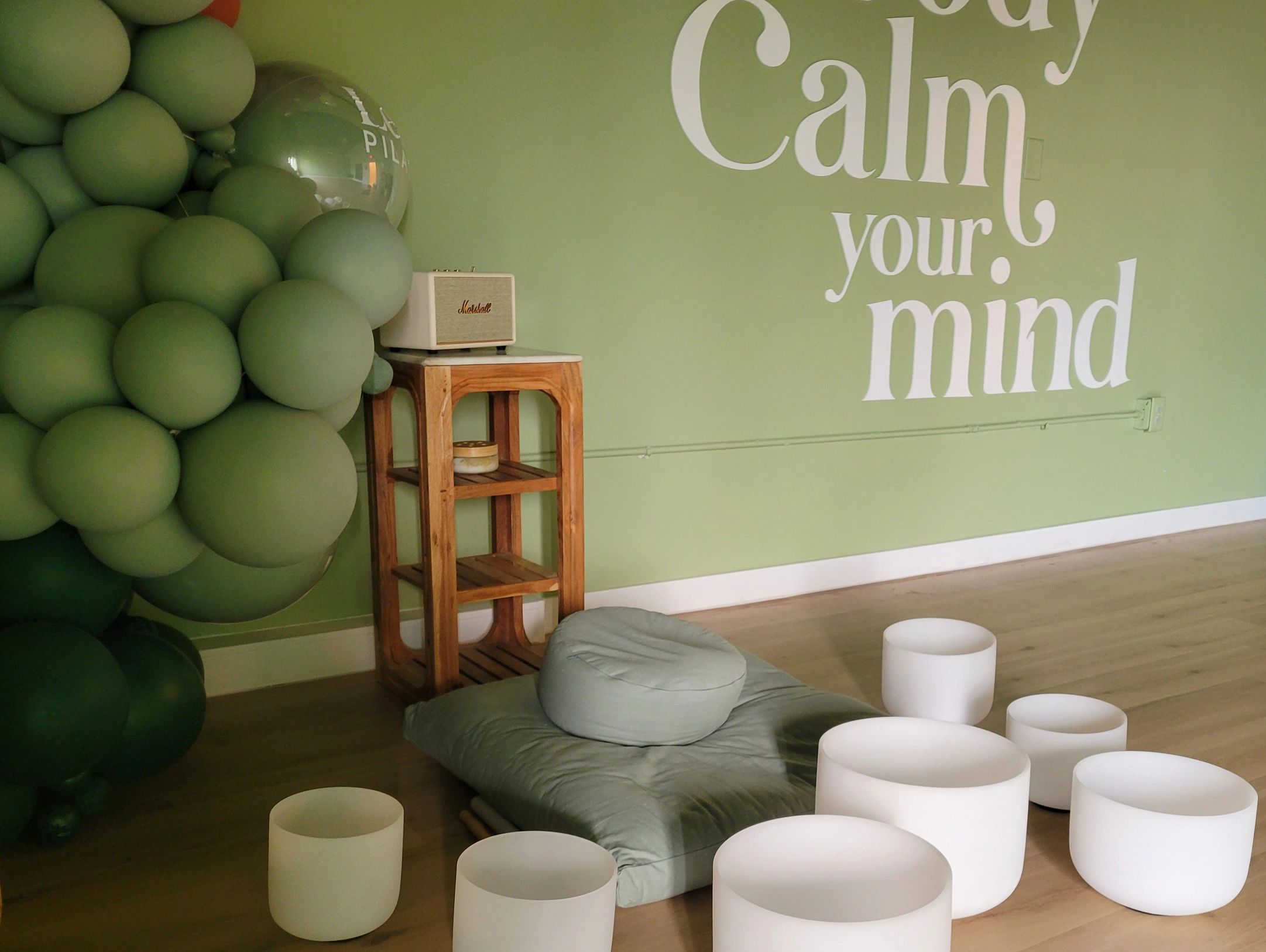 Seven crystal singing bowls spread in front of Leni's Pilates yoga studio wall, Calm Your Mind.