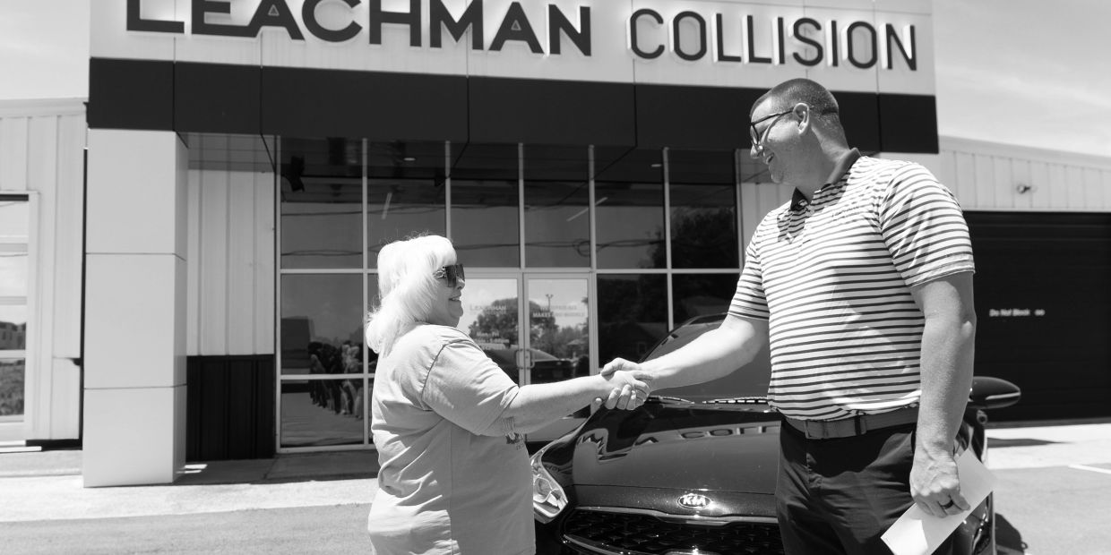 Two people shaking hands outside Leachman Collision.