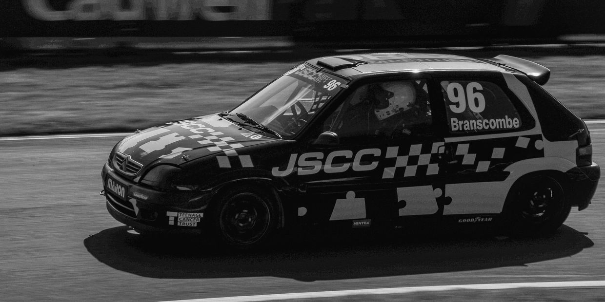 Black and white racing car number 96 on a track with sponsor logos.