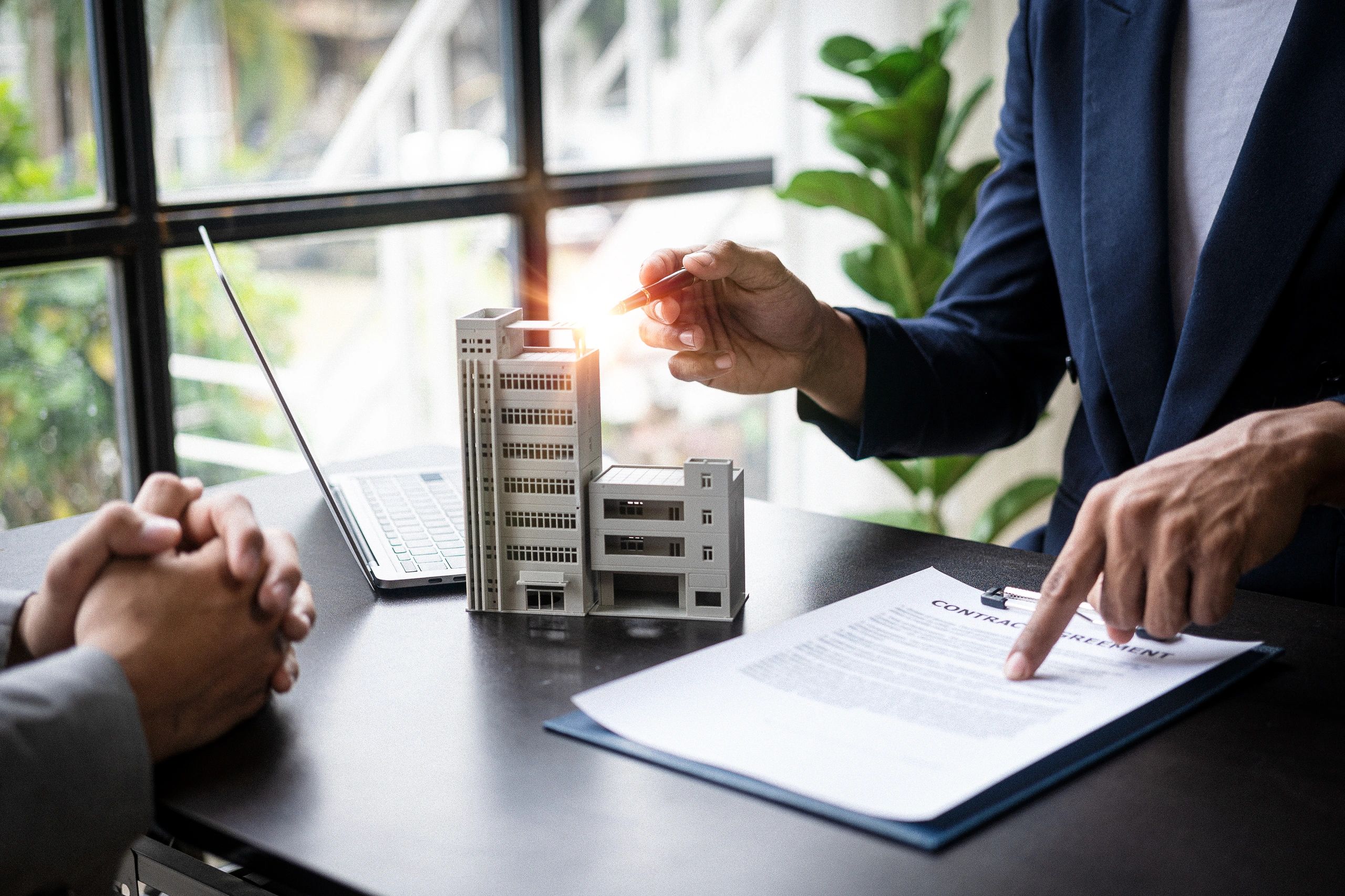 Real estate contract signing with building model.