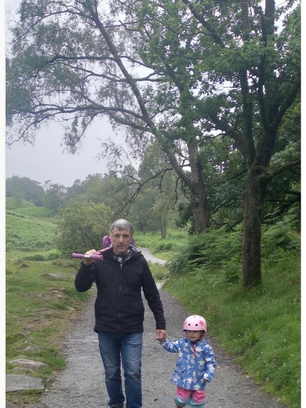 Man and child holding hands on a forest path.
