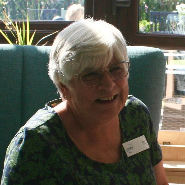 Elderly woman with white hair smiling indoors.
