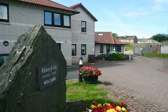 External view of Staveley House. Sunshine and blue skies. Large slate stone with Abbeyfield engraved