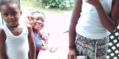 Children holding holiday gift bags with a woman smiling in the background.