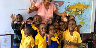 Teacher with smiling children in colorful school uniforms.