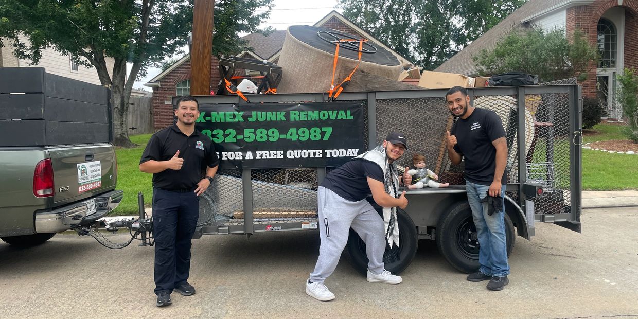 Three men posing with a junk removal trailer full of furniture and a baby doll. Eco-friendly junk removal, full service junk removal