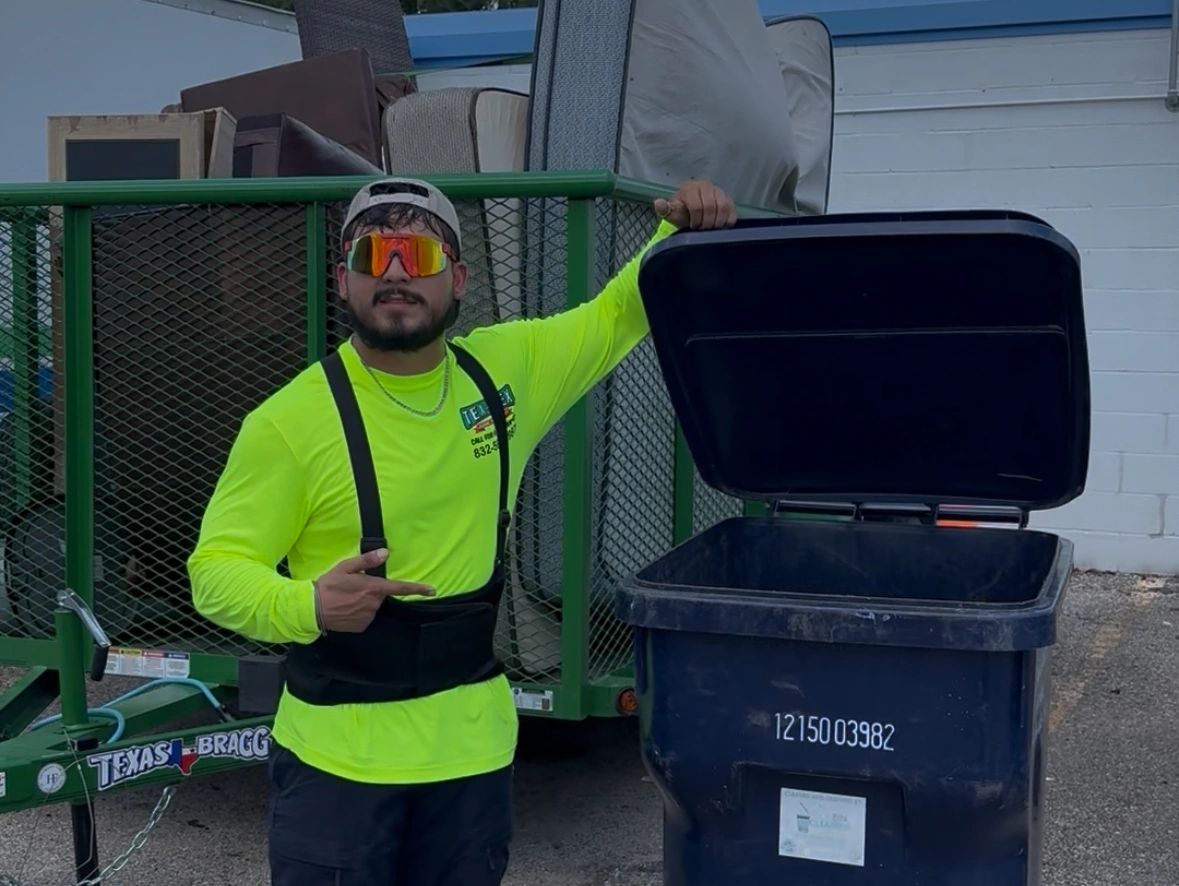 Tex Mex Expert in neon shirt posing with an open trash bin and loaded trailer behind, in Houston TX.