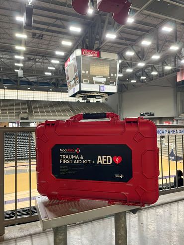 Red trauma and AED first aid kit in a sports arena.