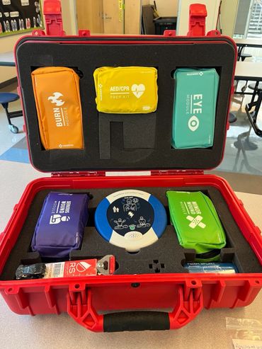 Red emergency medical kit with labeled modules for burns, eye, wounds, and CPR.