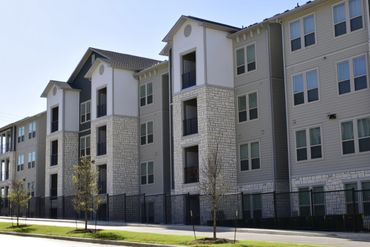 Modern apartment complex with stone and siding exterior under clear sky.