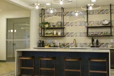 Modern kitchen island with pendant lights and patterned backsplash.