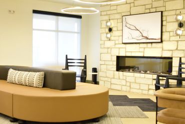 Modern living room with circular sofa and stone fireplace.