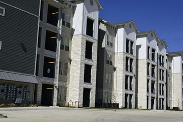 Modern apartment complex with stone and siding exterior under clear blue sky.
