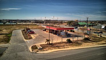 Gas station with red roof under clear blue sky in a suburban area.