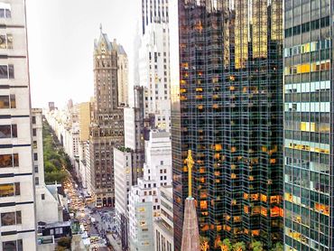 Cityscape with tall buildings and busy street traffic below at dusk.