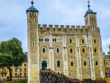 Historic stone castle with towers and battlements under a cloudy sky.