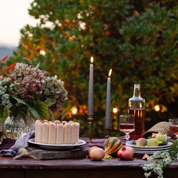 A cozy outdoor table with cake, candles, and autumn decor.