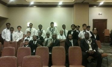 Group of men and boys dressed formally, posing indoors.
