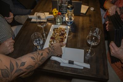 People sharing a meal with wine glasses around a wooden table.