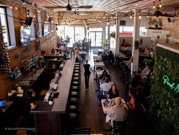Interior of a busy modern restaurant with patrons dining and string lights.