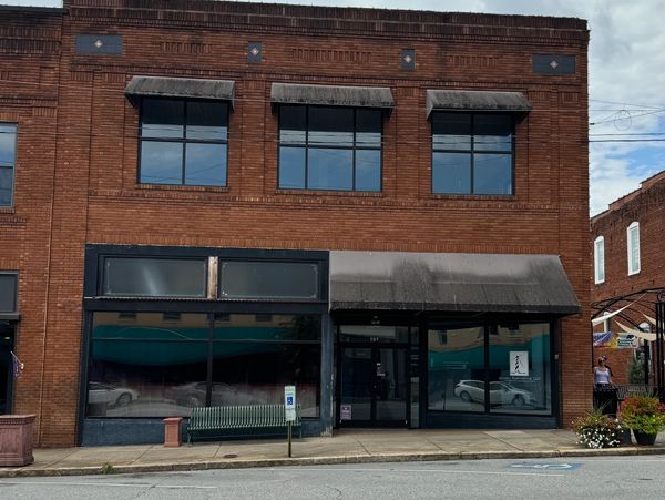 Empty brick storefront with large windows and awnings.