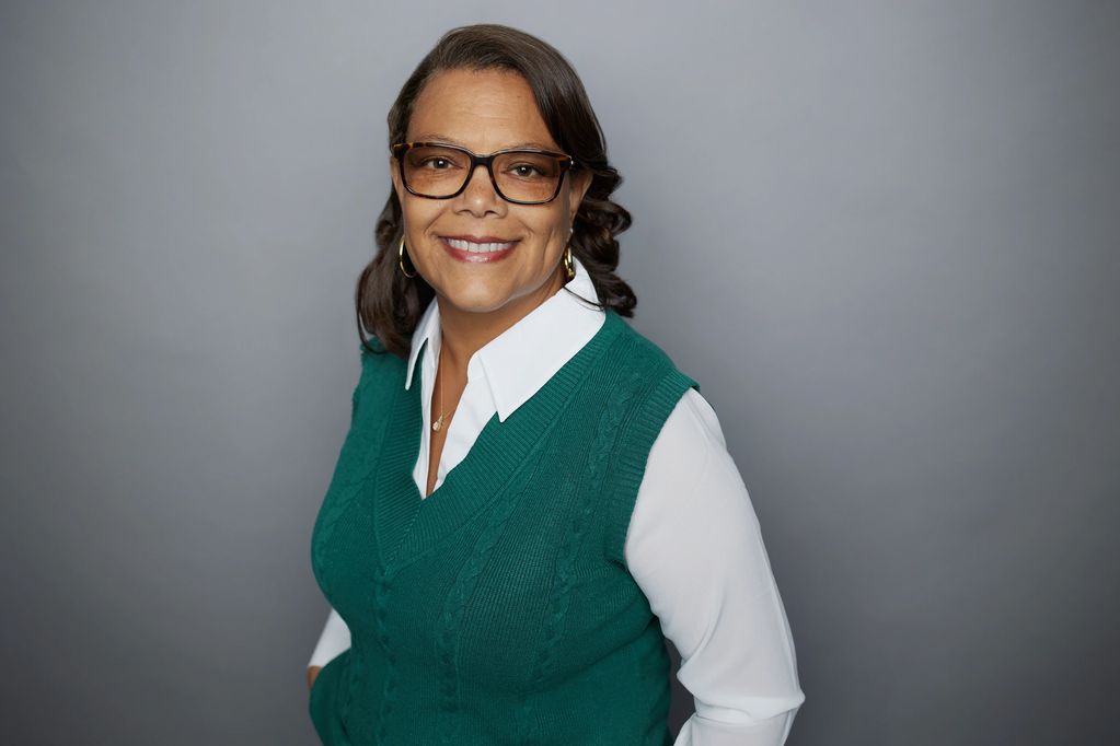 Woman wearing green and eyeglasses, facing camera and smiling
