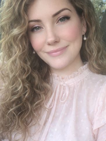 Woman with curly hair smiling gently.
