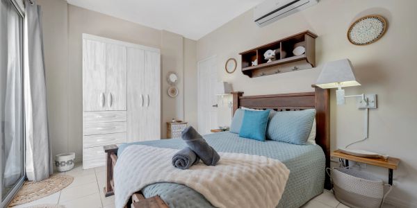Cozy bedroom with wooden furniture and soft blue bedding under natural light.