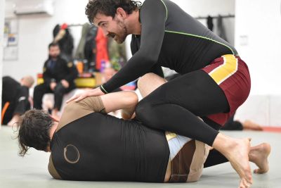 Two men practicing Brazilian Jiu-Jitsu on mats.