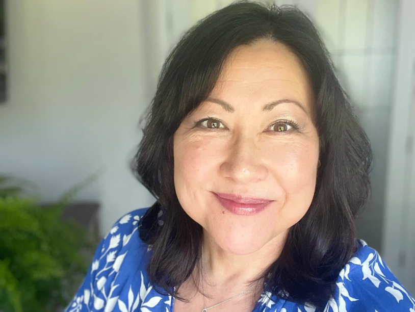 Smiling woman in a blue floral top.