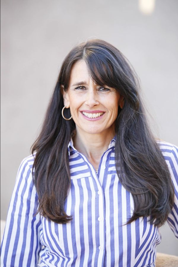 Woman with long dark hair smiling, wearing a striped shirt.