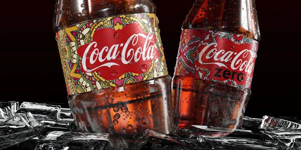 Two Coca-Cola bottles with colorful labels on ice, covered in condensation.