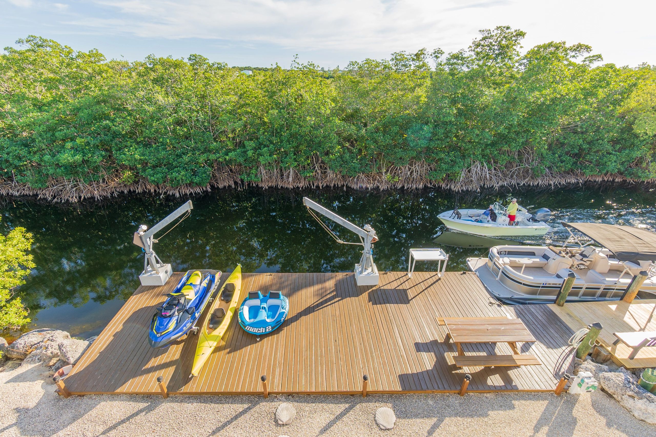 Dock at Airbnb with jet ski, tow toy, kayak, fish cutting station and boat overlooking mangroves.