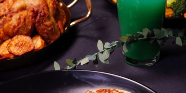 A gourmet meal with grilled fish, macaroni and cheese, asparagus, and a vibrant blue cocktail.