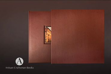 Two elegant brown leather-bound books side by side with a small image window in one.
