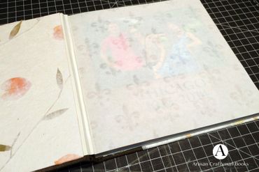 A handmade book with translucent floral pages on a cutting mat.