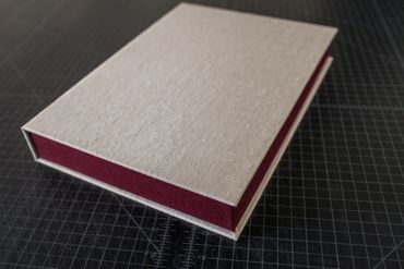Beige and maroon fabric box on a black grid surface.