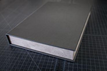 Close-up of a textured book spine on a grid cutting mat.