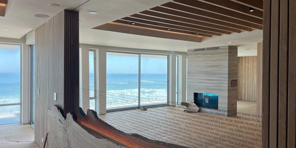 Modern room with large windows overlooking the ocean and a stylish fireplace.