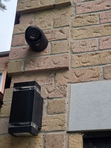 Security camera mounted on a brick wall.