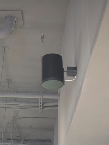 Black cylindrical wall light fixture on a white wall.