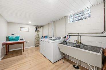 Full laundry room stocked with soap and dryer sheets with a full utility tub.