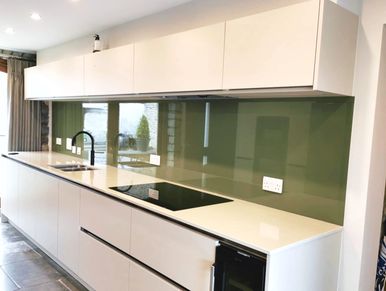 Modern kitchen featuring a sleek tinted glass splashback, adding a stylish and reflective finish