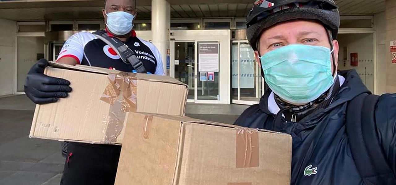 Two masked men holding cardboard boxes, ready for delivery or donation.