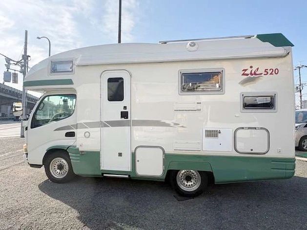 White and green camper van parked outdoors.